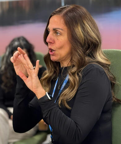 Interpreting in office interpreter in black, hands in the air with a visitor badge around her neck